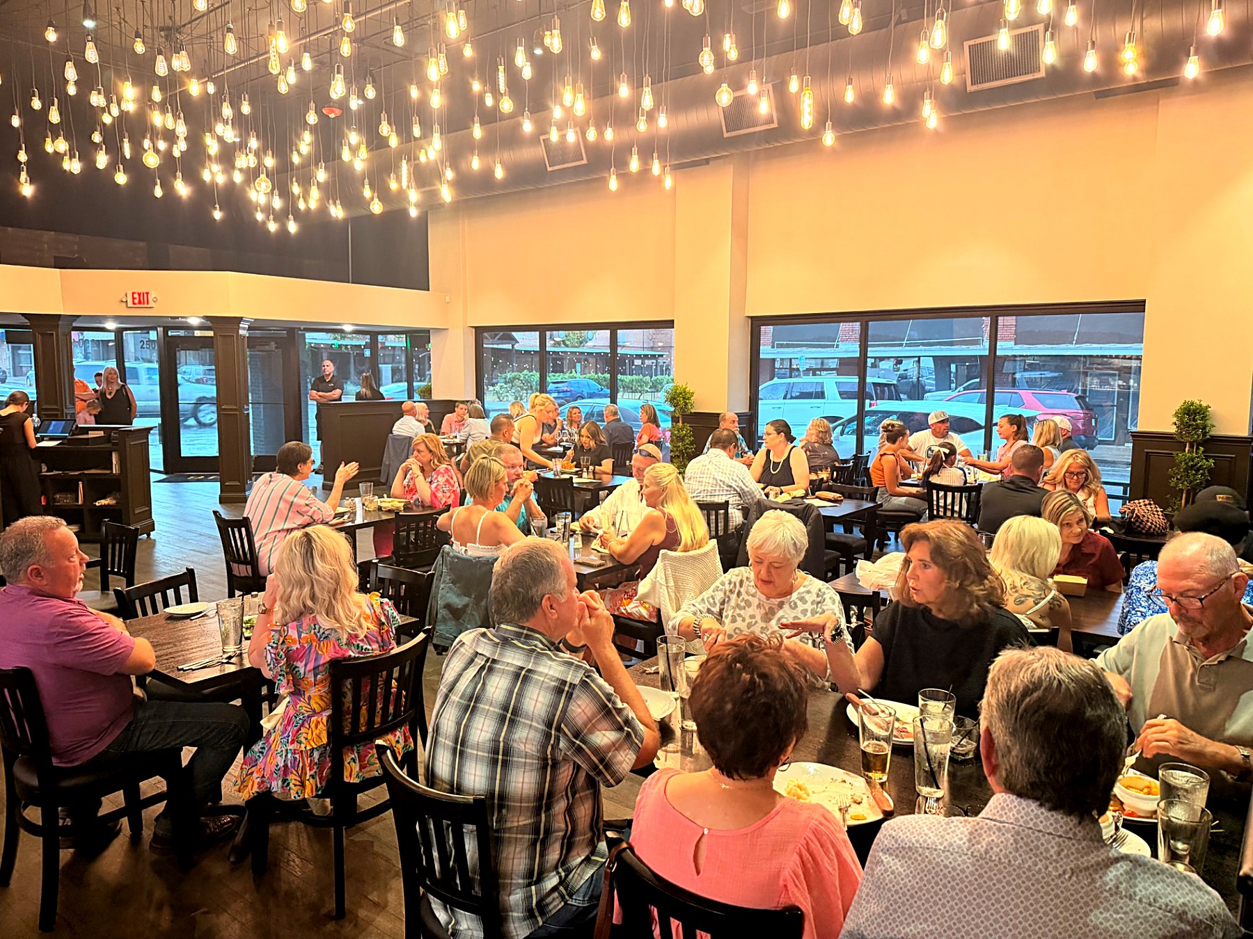 A full dining room at 1846 beneath hundreds of hanging Edison bulbs